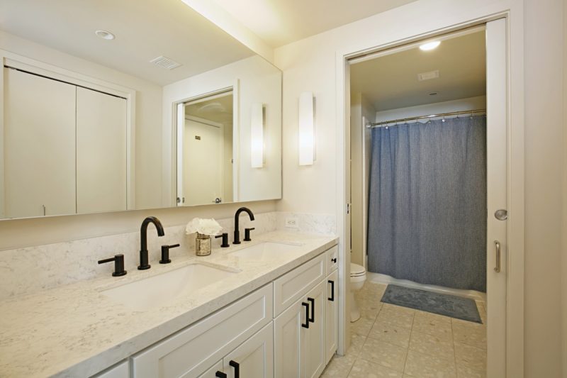 Bathroom with dual sink vanity and combined shower-bathtub.