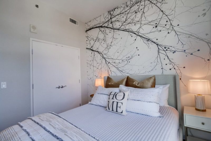 Guest bedroom with stylish tree accent wall.