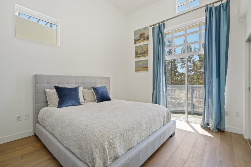Guest bedroom with plenty of natural light coming from the glass doors to the balcony.